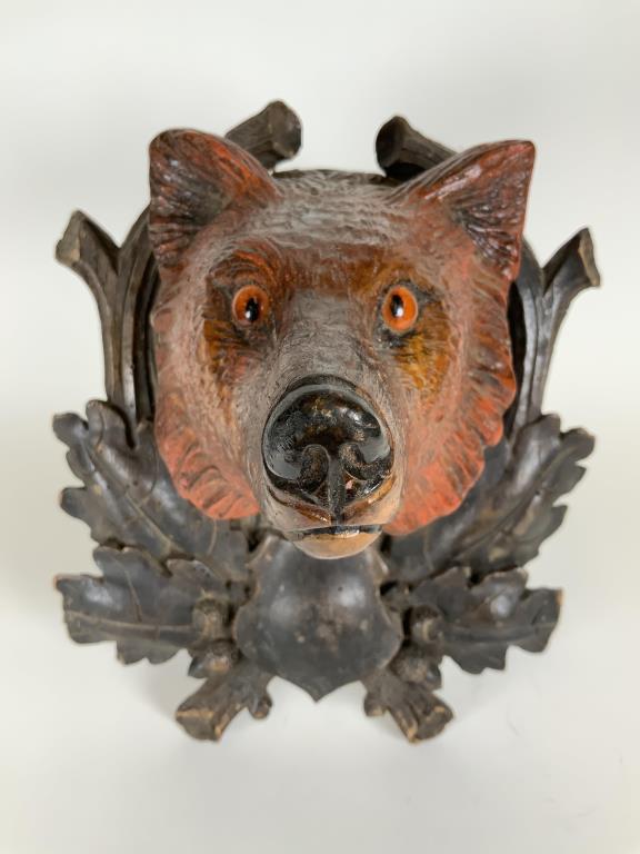Black Forest wolf head plaque with glass eyes;: wolf head with glass eyes, 12.25 inches tall, 9.5 inches wide, 8 inches deep from wall, some small chips and wear to leaves, repair to the top of mounting