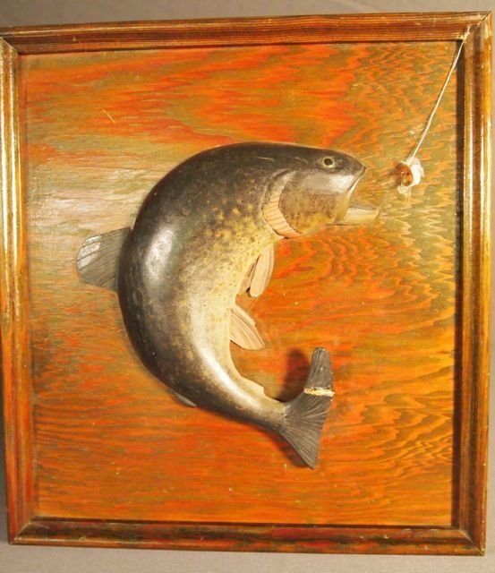 Carved Wood Trout on Wood Panel: Carved wood trout rising to a fly on wood panel, trout measures 7'6," panel 12'6" x 11'5." Label on back states "Carved and Painted by Lloyd H. Thomas at Camden, Maine 1932." Damage to tail.
