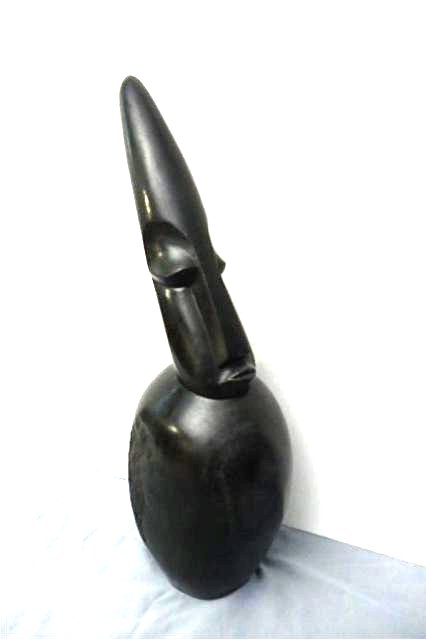 Stone Carving: Elongated head, round body, Measures 24.5"T x 6" W x 9"D , Signed Muhendo. M. Weight approx. 40-50 lbs. Artist: finished by Simba Title: Cone head spy Medium: Spring stone
