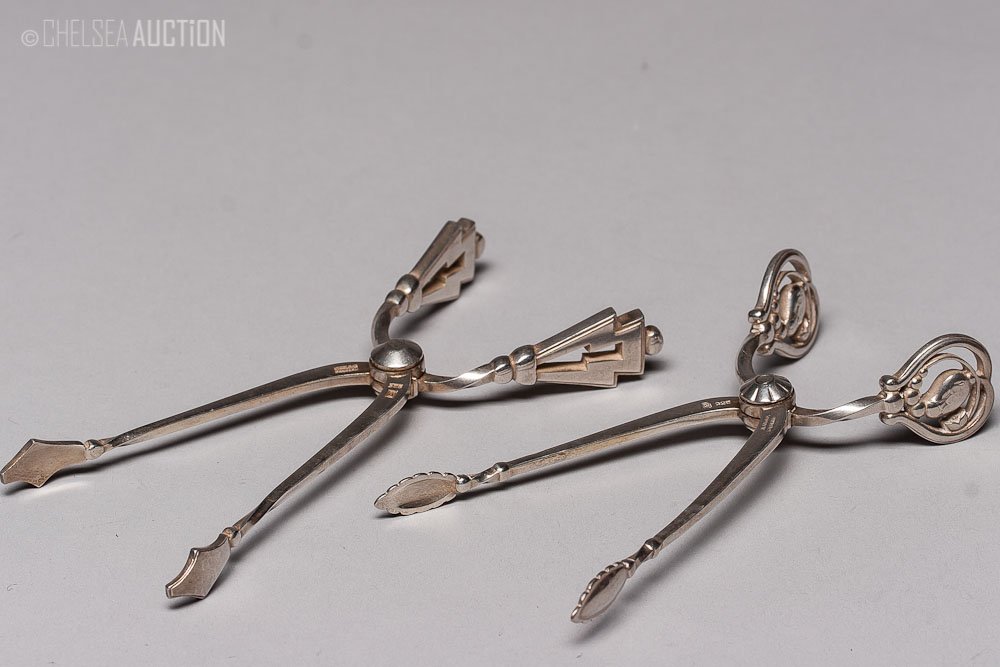 Old Silver Sugar Tongs By George Jensen: Two old silver sugar tongs. Hallmarked Denmark, 925, maker mark by George Jensen. SIZE: Small opener: L 4 in x W 1 in (10 cm x 2.5 cm); Large opener: L 4 1/4 in x W 1 1/4 in (10.5 cm x 3.5 cm)