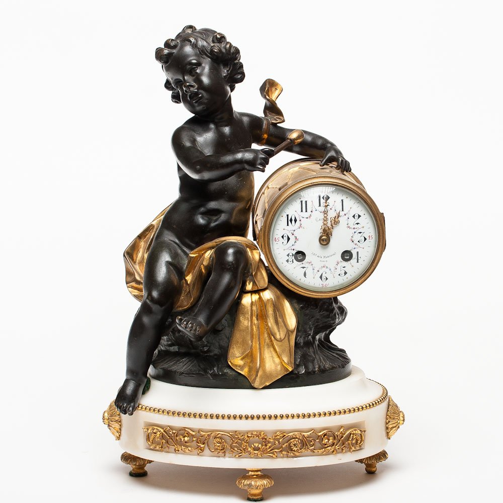 A FRENCH BRONZE, GILT-BRONZE & MARBLE MANTEL CLOCK: A French bronze and marble mantel clock in form of cupid playing drum. Cupid figure after signed "L. Bureau" after Leon Bureau (1866-1906), enameled dial signed "Caisso & Cie., LBd de la Madelaine, Pa