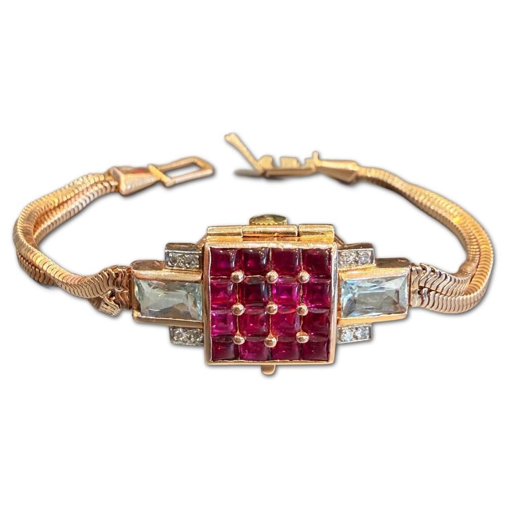 14K RG Mid Century Ruby, Aquamarine, & Diamond Ladies Concealed Face Wristwatch: 14K Rose Gold Mid Century Ruby, Aquamarine, & Diamond Ladies Concealed Face Wristwatch Containing Twelve (12) Square Cabochon Cut Rubies Weighing Approximately 1.20cts in Total Carat Weight. The 