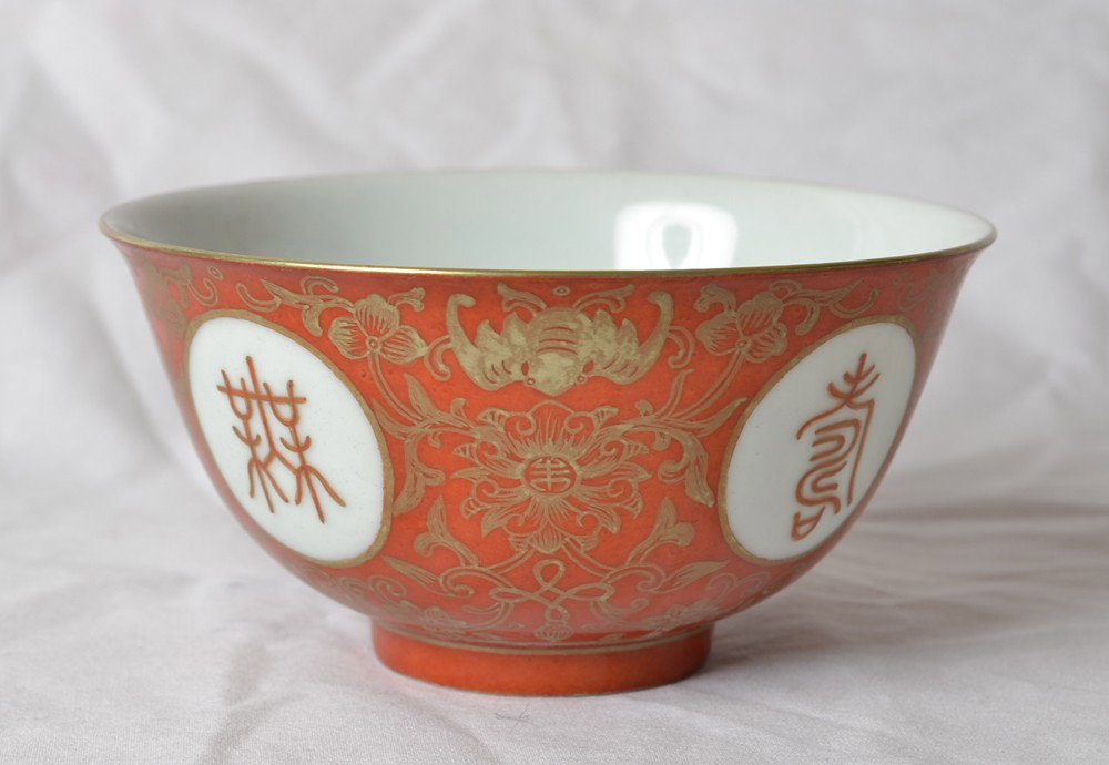 RED AND WHITE PORCELAIN BOWL: With Wan Shou symbols and bats and gilded rim. Qianlong red mark. 3.125" H x 5.125" DIA.