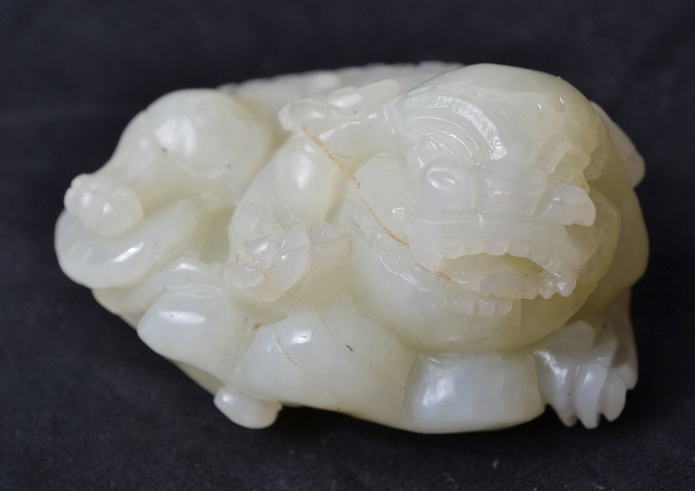 CARVED JADE FOO DOG: Carved foo dog seated on top of ruyi. 2.25" L.