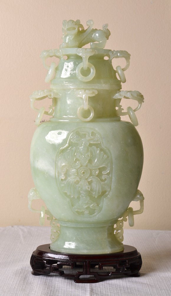 LARGE SERPENTINE JADE COVERED URN: Carved urn with loose rings, bats and foo lion at top. 12" H, and 13.5" H with stand. Repair and small chip to one ring.