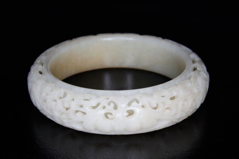 CARVED JADE OPENWORK BANGLE BRACELET: With raised secondary openwork of bats and vines. 3.125" outside diameter, 2.25" inside diameter. 20th century.