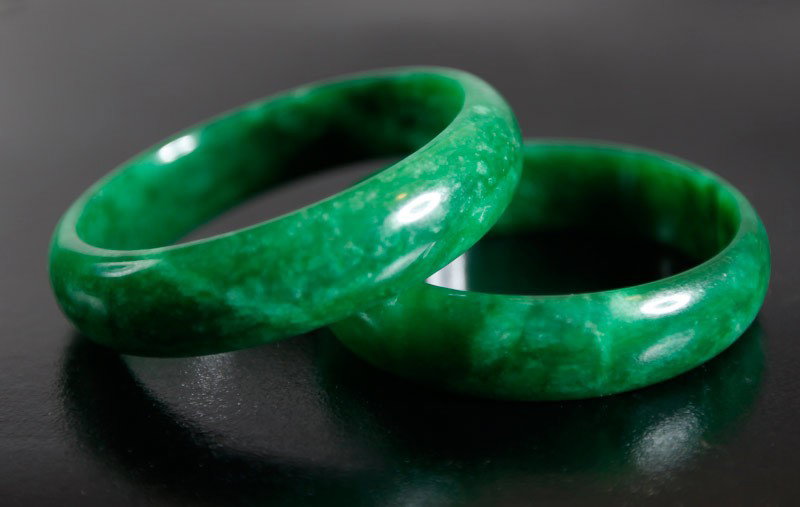 PAIR OF CHINESE CUI JADE BANGLES: Smooth carved, one slightly larger than the other. Smallest measures 2.25" inside diameter, 2.625" outside diameter.
