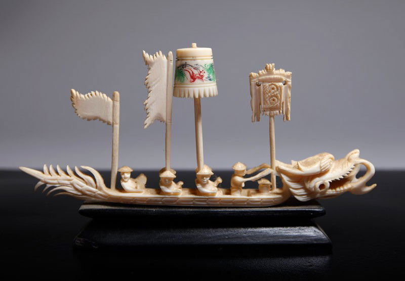 CHINESE IVORY DRAGON BOAT: This item is not available for international shipping. This item will only be shipped within the United States. Carved boat in dragon form with one directing boat, additional flags and on carved wood