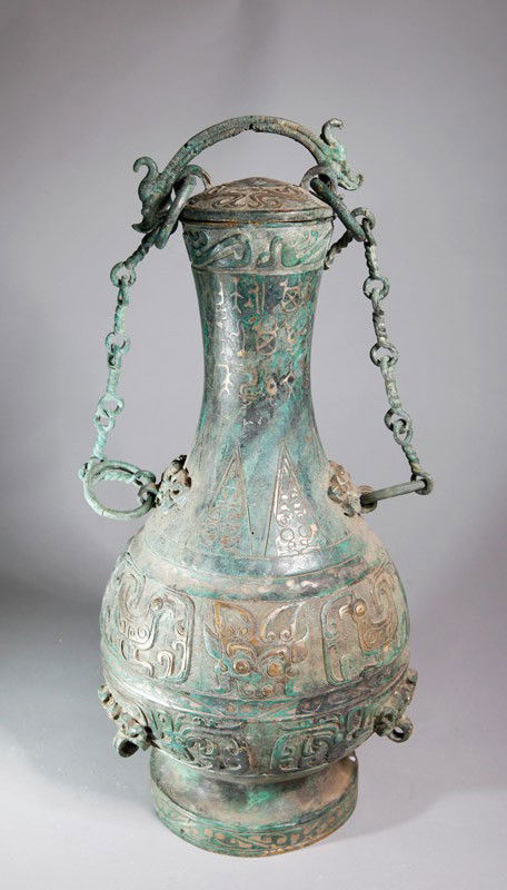 CHINESE BRONZE VASE WITH LID: With beast, caligraphy, and geometric designs. Lid with loose rings, two loose ring handles and chain for hanging. 15.25" H x 7.875" W.