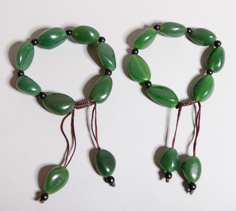 PAIR OF CHINESE MO YU JADE BRACELETS: Each with 7 beads separated by darker beads and tassel beads on the end.