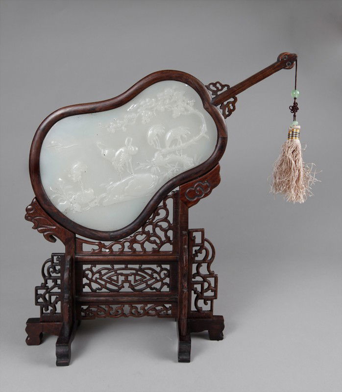 CHINESE JICHI WOOD AFGHAN JADE SCREEN: Mounted as a fan form, with cran carvings, attaches to a carved openwork wood stand. 13.625" H x 14" W.