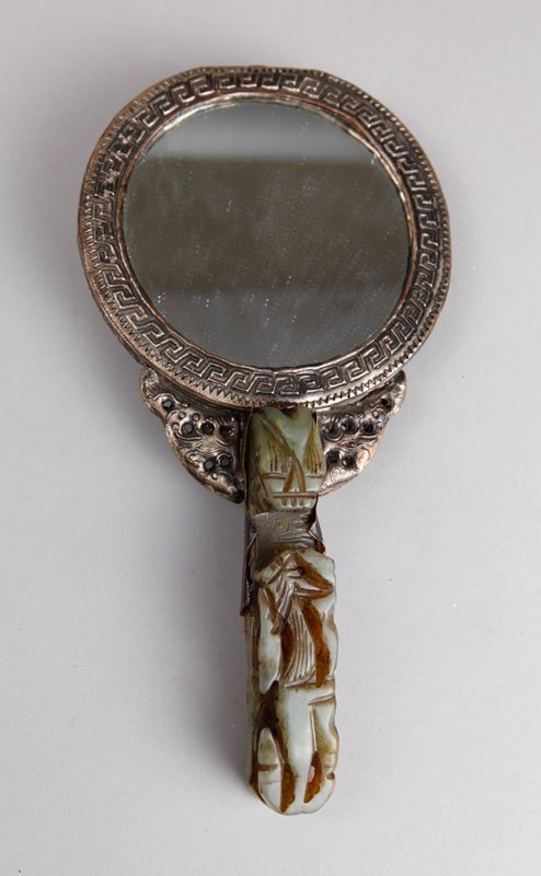 CHINESE HAND MIRROR WITH JADE BELT HOOK: The belt hook in dragon form, the remainder with tooled copper painted silver and two gemstones. Back of mirror base with four character mark in a square. 8.75" L. Some denting near top of mirror fram