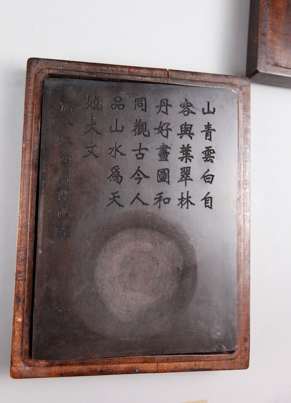CHINESE TUI GENG TANG INK STONE IN BOX: Stone with caligraphy lines, in custom carved wood box with etched caligraphy and seal mark. Box measures 2.125" h x 8.5" L x 6.5" W. Box lid with repair to bottom edge.