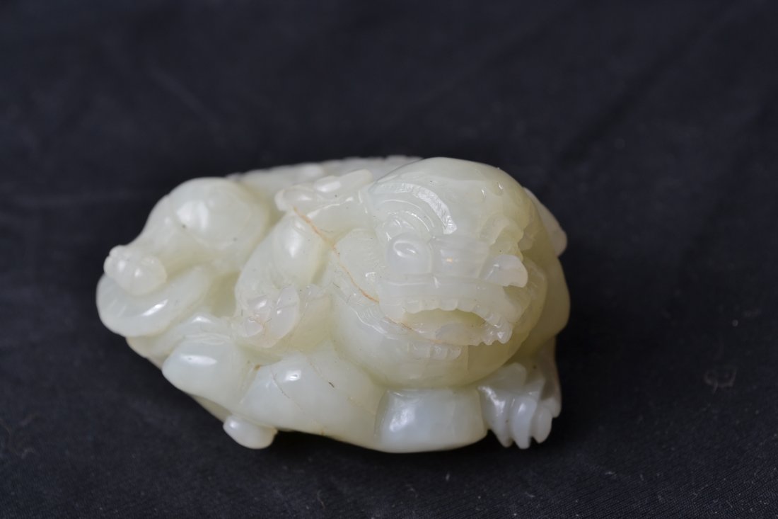 CHINESE JADE FOO DOG: Carved foo dog seated on top of ruyi. 2.25" L.