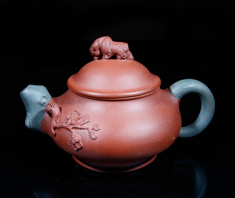 CHINESE YIXING POTTERY TEA POT: Two-tone, with raised mei flower near spout and water buffalo lid. Two character mark on underside. 3" H x 5.25" W. Excellent condition.
