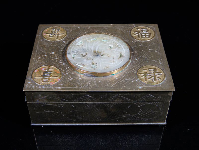 CHINESE EXPORT BRASS AND JADE CIGARETTE BOX: Brass box decorated with etched floral symbols and four applied brass circles of symbols. Center with light celadon jade carving of a bird, with original nice patina beneath. Etched CHINA on underside