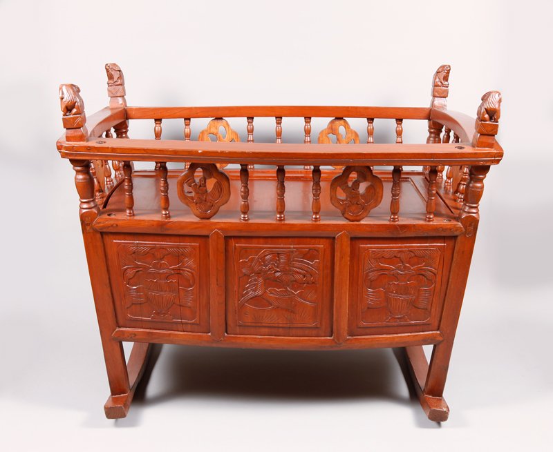 Chinese Export Rosewood Cradle: The base finely carved depicting alternating panels with birds and vases. The head carved with panel of two dragons and pearl, the foot carved with panel of figure riding a foo dog. Carved spindles se