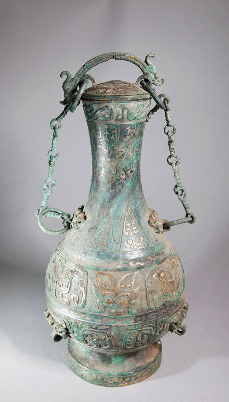 CHINESE BRONZE VASE WITH LID: With beast, caligraphy, and geometric designs. Lid with loose rings, two loose ring handles and chain for hanging. 15.25" H x 7.875" W.