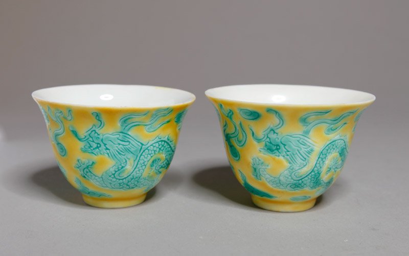 PAIR OF CHINESE PORCEALIN TEA CUPS: In yellow glazed with carved dragons, flaming pearl and ruyi in green. Six character mark in blue. 1.75" H x 2.5" DIA.