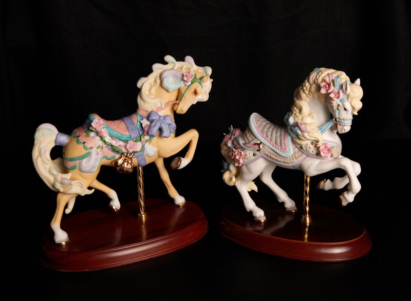 2 Lenox Porcelain Carousel Horse Figurines: Includes a 1987 carousel horse with pink flowers cascading braided mane, and attached to hardwood base. Together with a 1989 yellow horse with pink flowers, purple bows, and attached to hardwood base.