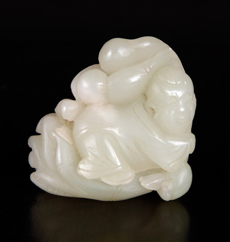 Chinese Carved Jade Boy Figure: In light celadon/white, finely carved to depict a robed boy seat upon Buddha's hand, holding ruyi. 2" H x 2" W x 1.125" D. Excellent condition.