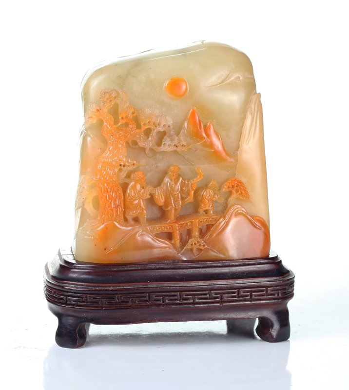 Chinese Shoushan Carving on Stand: One side carved to depict intricate figures on a bridge beneath lingzhi and in mountain setting. Other side carved with lingzhi protruding from mountain. Resting on custom carved wood stand with Greek