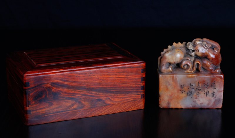 Chinese Shoushan Seal in Wood Box: Numerous character seal, one of the four sides carved with caligraphy, the top carved with three-dimensional chilong. In custom carved wood box with felt top and bed. Seal measures 3.125" H x 3" L x 1