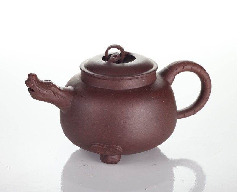 Chinese Zisha Clay Teapot: Resting on three feet, with dragon head spout, dragon tail handle, and loose ring on lid. Four character mark on underside. 3.25" H x 5.5" L x 3.25" W. Excellent condition.