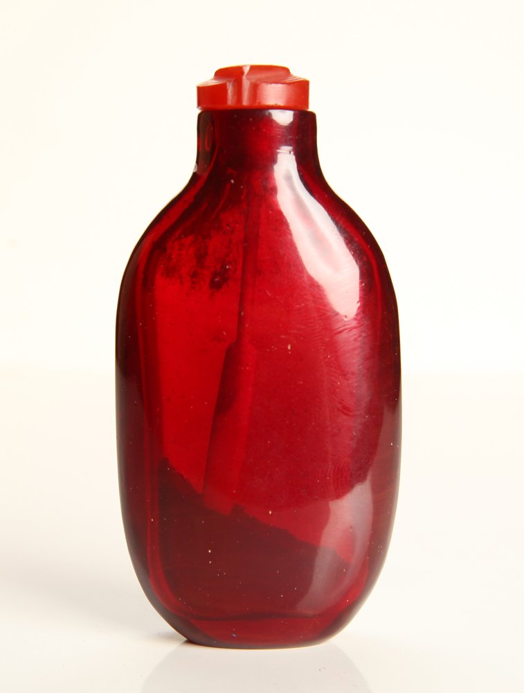 Chinese Peking Glass Snuff Bottle: In red glass with carved carnelian lid. 2.875" H x 1.375" W. Excellent condition.