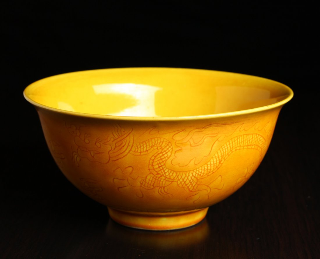 Chinese Saffron Incised Porcelain Bowl: The interior incised with floral design, the exterior with dragon, phoenix, ruyi clouds and stiff petals. Six character mark in black on underside. 3" H x 6.125" Dia. Excellent condition.
