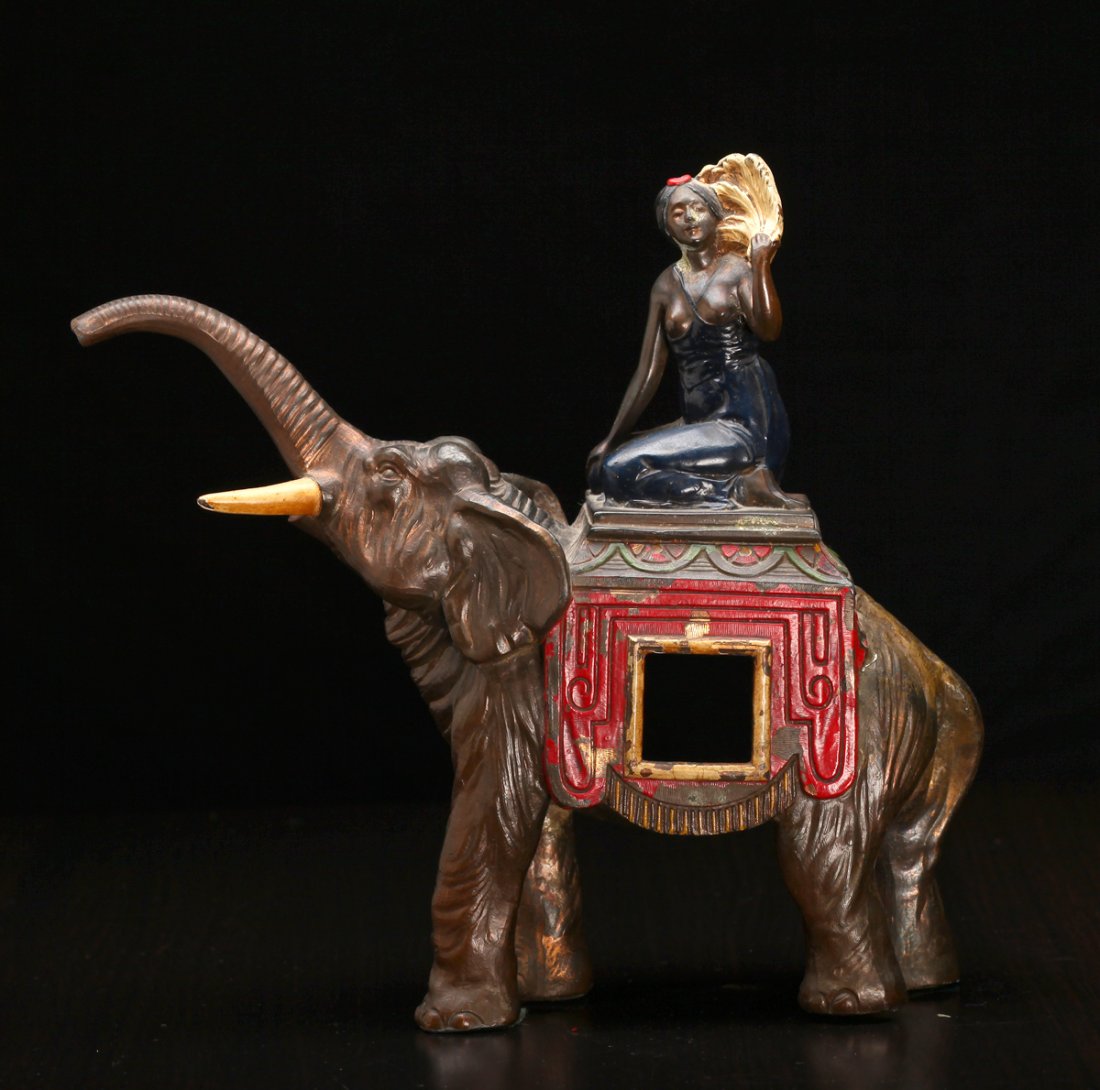 Antique Asian Bronze Candle Holder: Casted to depict an elephant, with female figure atop holding fan, with painted highlights. 7.625" H x 9.5" L x 2.75" W. Lacking one tusk, wear to painted highlights throughout.