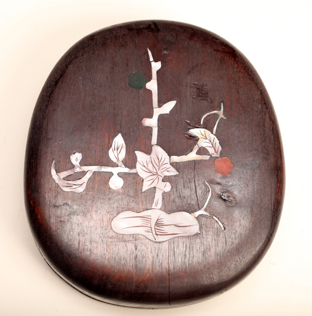Chinese Inkstone in Hardwood Inlaid Box: Oval form ink stone with well and caligraphy. Housed in custom carved hardwood box, inlaid with MOP on lid of floral branch. Inkstone measures .75" H x 5.625" L x 4875" W. Excelent condition with natu
