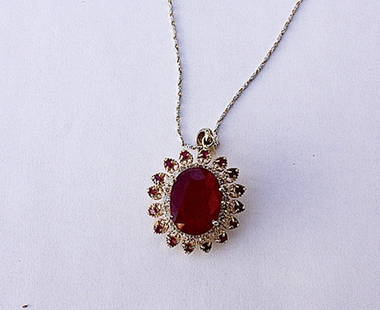 Ladies14K Ruby and Diamond pendant necklace: Ladies Ruby and Diamond Pendant containing in the center one oval faceted ruby of approx. 14.12 cts. with surrounding round faceted rubies of approx. 1.0 cts and surrounding diamonds of approx. .90