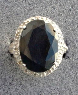 Ladies Sapphire and Diamond ring: Ladies fancy Sapphire and Diamond ring containing one oval shaped (faceted) sapphire of approx. 9.80 cts. And Diamonds of approx. .07 cts. Set in a very ornate detailed sterling silver setting. Mint