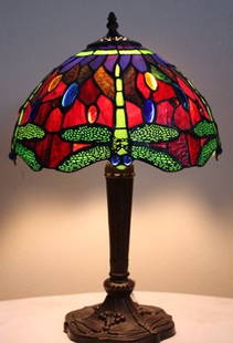 Jeweld Dragonfly lamp: "Dragonfly" lamp measuring approx. 19X11x11 with hand cut glass and jeweled glass in the shade as well as filagree with a dragonfly reliefs in the base. Very good condition.