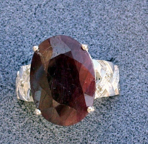 Ladies Ruby and Diamond ring: Ladies fancy Ruby and Diamond ring containing one oval shaped ruby of approx. 9.80 cts. and Diamonds of approx. .05 cts. Set in a very ornate detailed sterling silver setting. Mint condition.