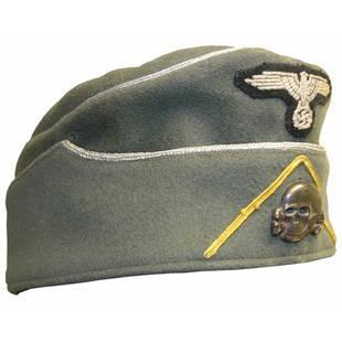 [WAFFEN SS CAVALRY CAP]: Gray overseas cap worn by an SS cavalry officer. The front center above flap displays a 1934 pattern machine woven Nazi eagle with swastika in silver bullion. A patinaed Totenkopf (death head skull) i