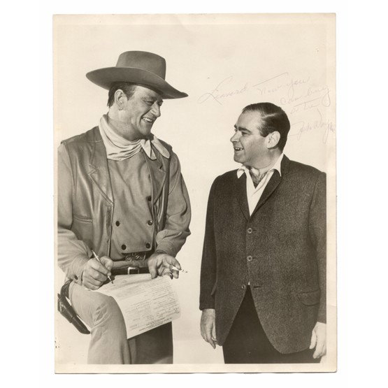JOHN WAYNE: (1907-1979). Leading man of Western and action film genre, "The Duke" became one of the most successful stars in Hollywood. ISP, b/w matte, three-quarter length casual portrait in Western attire with 