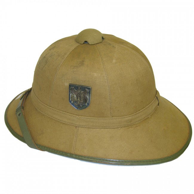 [GERMAN PITH HELMET]: Nazi World War II helmet worn during their African Campaign. A German Nazi Afrika Corps tropical pith helmet manufactured by Clemens Wagner, Model SE 56, Size 9. Shell, chinstrap and inside red lining