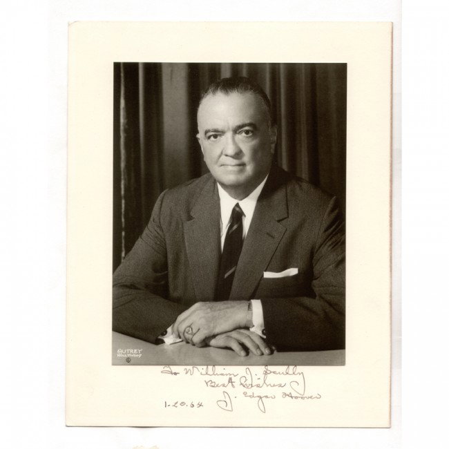 J. EDGAR HOOVER: (1895-1972). Controversial director of Federal Bureau of Investigation (1924-72). ISP [Max Mun Autrey], b/w, 6½"x8¼" half-length seated portrait. Boldly signed, adding sentiment and "1-20-64." Mount