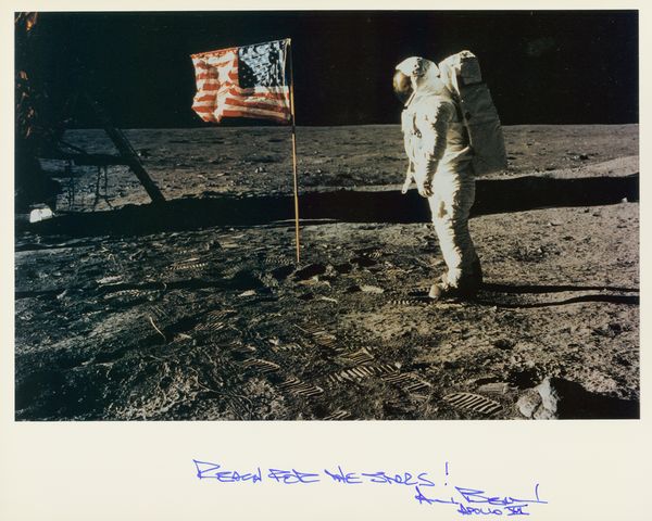 ALAN BEAN SIGNED PHOTO ON MOON: 451. ALAN BEAN (b.1932). American astronaut and artist; Apollo XII and Skylab III veteran; fourth man to walk on the moon. SP, color lithograph, overall 10"x8" portrait standing near American flag on