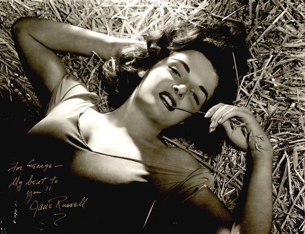JANE RUSSELL SIGNED OVERSIZE PHOTO "THE OUTLAW": 872. JANE RUSSELL (b. 1921). Voluptuous American leading lady who came to Hollywood when an agent sent her photo to producer Howard Hughes. Starring her in The Outlaw (1943), his publicity campaign le