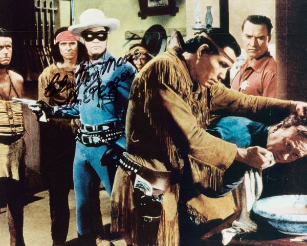 CLAYTON MOORE SIGNED LONE RANGER FILM STILL PHOTO: 948. CLAYTON MOORE (1908-1999). Tall leading man of '40s second features, later famous as television's Lone Ranger. SP, color, 10"x8" film still of the "Masked Man" and Tonto. Boldly signed across his