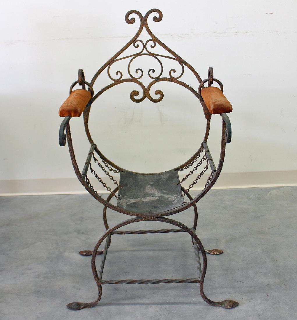 ANTIQUE IRON RENAISSANCE THRONE CHAIR: Wrought iron campaign chair with upholstered arms and high back. Metal seat is held in place by 8 suspended chains. 26" x 20" x 42".