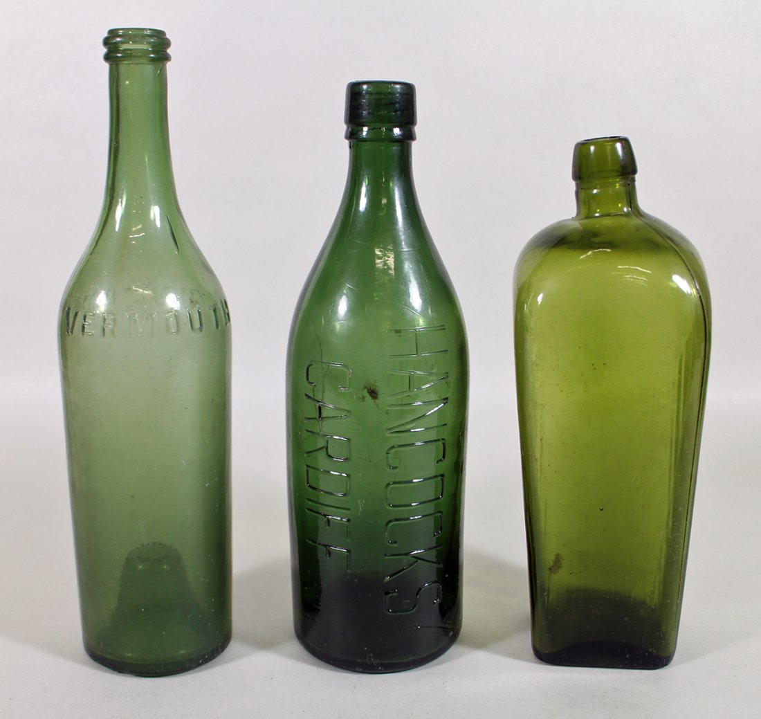 (3) ANTIQUE GREEN GLASS BOTTLES: Includes a Cinzano vermouth bottle with a steep rise pushed up pontil, a Hancocks Cardiff bottle, and a titled top bottle marked W or M. 10.5" to 13" tall.