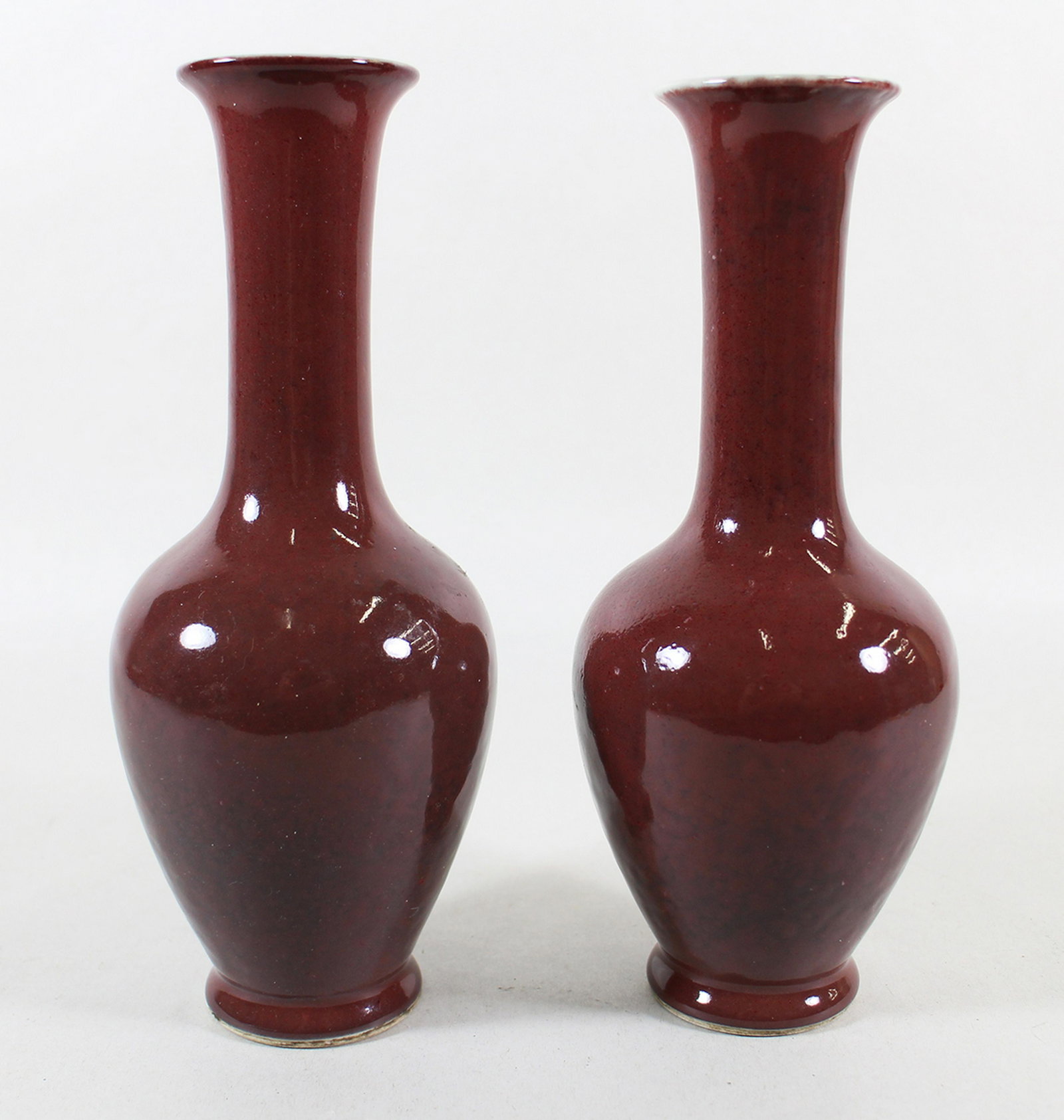(2) CHINESE OX BLOOD VASES: Pair of Chinese ox blood vases with Kangxi mark on bottom. 8.5" tall.