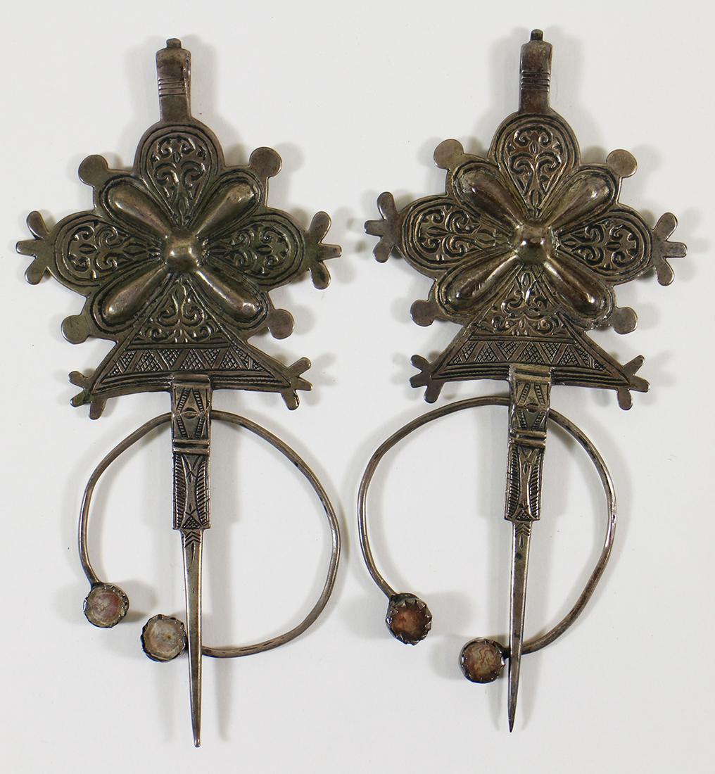(2) NORTH AFRICAN FIBULA GARMENT FASTNERS: A pair of berber silver fibula tizerais used a garment clasps. They have agate stone in a semi circle. They are 7 1/2" x 3 1/2".
