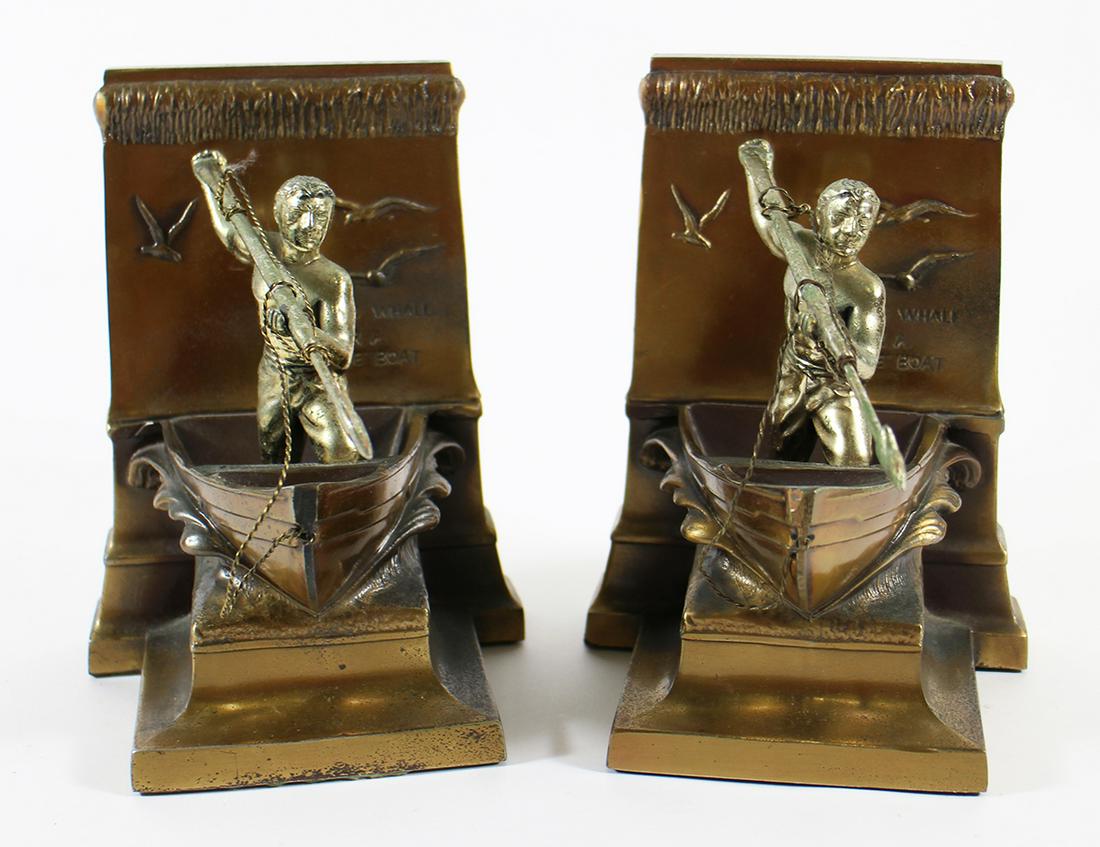 BRONZE WHALER BOOKENDS: A pair of bronze bookends of a New Bedford Boston whaler with a harpoon. It reads on front, "A Dead Whale or a Stove Boat" and on reverse, "In honor of the whaleman whose skill hardihood and daring br