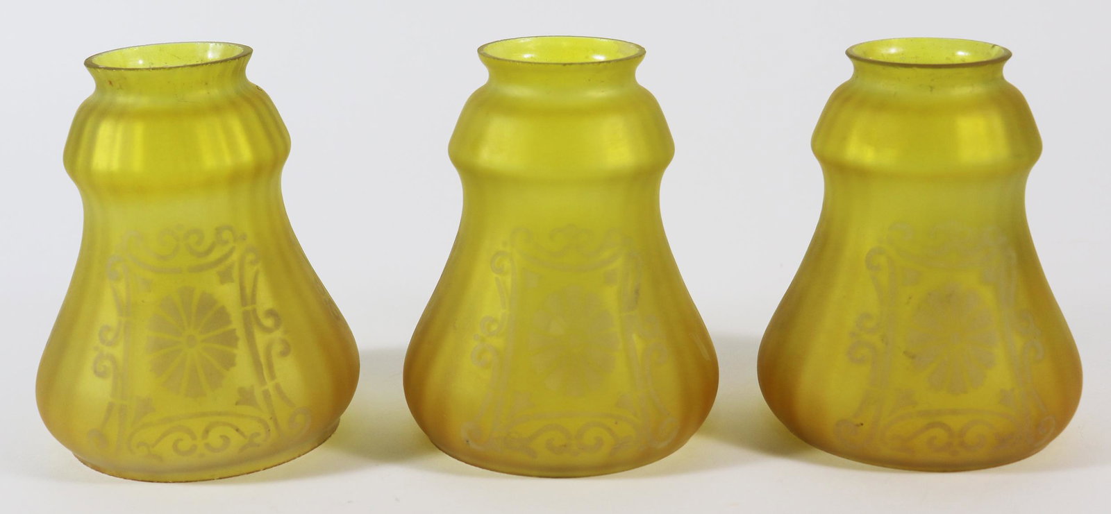 (3) ANTIQUE YELLOW GLASS GLOBE SHADES: Set of three antique yellow with white design lamp globe shades. Originally came from a lamp that was dated 1906. Some small chips. Approximately 5.25" long, 2" opening.