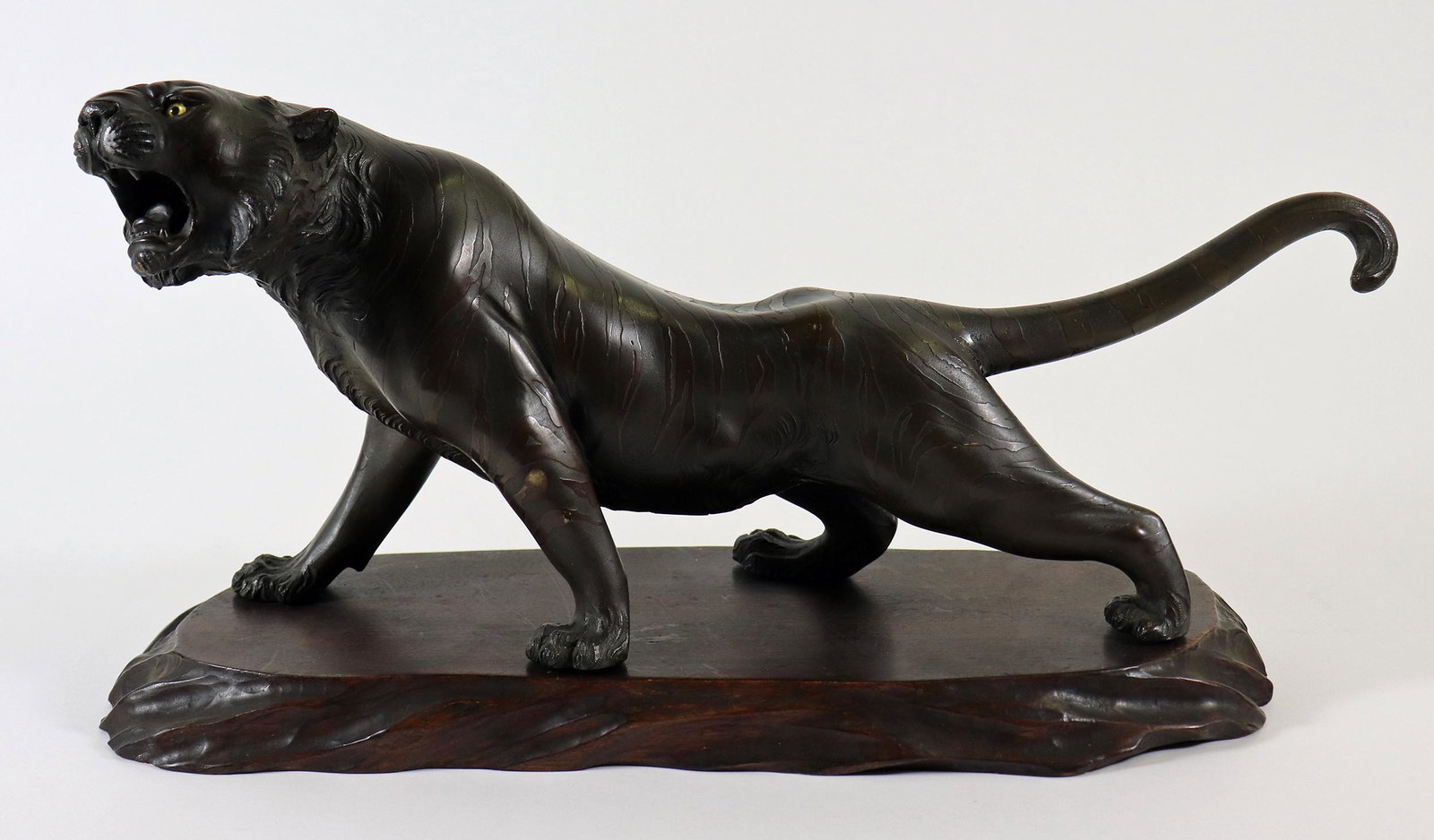 JAPANESE MEIJI PERIOD TIGER w/ GLASS EYES: Antique Japanese Meiji period tiger sculpture with stripes and glass eyes. Seal / stamp mark on bottom. 15.5" L x 7" H.